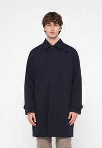 Tmavomodrý trenčkot so širokým golierom, zapínaním na gombíky vpredu a bočnými vreckami. Má priliehavý strih a hladkú textúru.