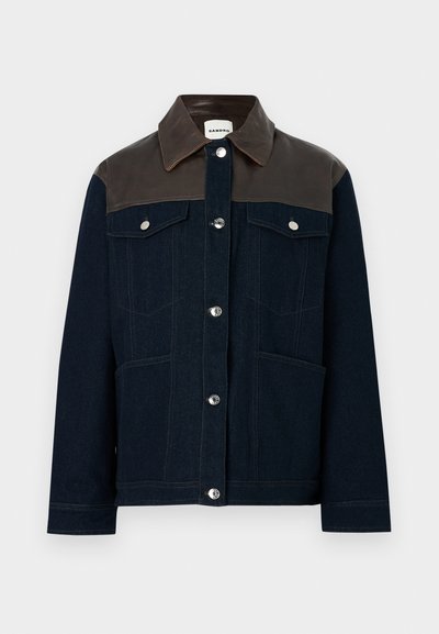 Kurtka dżinsowa z ciemnoniebieską korpusą, brązowym skórzanym yoke na ramionach, srebrnymi napami, dwiema kieszeniami na piersi oraz kontrastowymi detalami przeszyć.