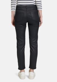 Schwarze, lederähnliche Slim-Fit-Hosen mit mittelhohem Bund und Fünf-Taschen-Design, das eine glatte Textur und subtile Nähdetails aufweist.