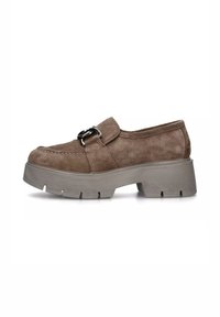 Scarpa slip-on in camoscio marrone con punta rotonda, suola piatta grigia e una fibbia decorativa in metallo sulla parte superiore. Dettaglio della superficie testurizzata visibile.