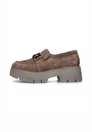 Scarpa slip-on in camoscio marrone con punta rotonda, suola piatta grigia e una fibbia decorativa in metallo sulla parte superiore. Dettaglio della superficie testurizzata visibile.