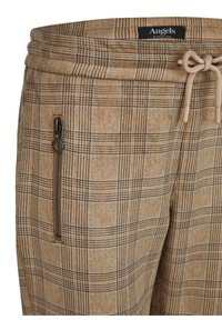 Pantalon à carreaux beige et marron avec une poche zippée devant, une taille à cordon de serrage et une étiquette de marque "Angels" à l'intérieur de la ceinture.
