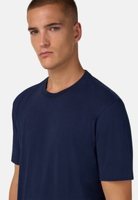 Námořnická modrá bavlněná tričko s kulatým výstřihem a krátkými rukávy, vyznačující se hladkou strukturou a jednoduchým designem bez vzorů.