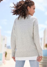 Light gray knitted sweater with a ribbed hem, relaxed fit, and dropped shoulder seams, layered over a white shirt. Casual style.