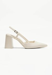 Escarpins à talon slingback à bout pointu en cuir verni crème brillant, dotés d'un talon bloc et d'une sangle réglable avec une boucle métallique.