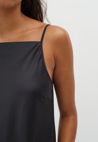 Czarna satynowa kamizelka na cienkich ramiączkach, z kwadratowym dekoltem i gładką teksturą. Posiada minimalne szwy i luźny krój.