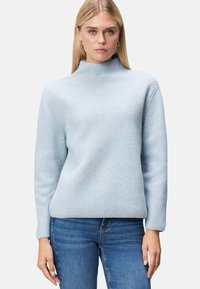 Hellblauer, gerippter Rollkragenpullover mit langen Ärmeln, entspannter Passform und strukturiertem Stoff; kombiniert mit Jeans.