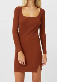 Robe côtelée à manches longues en orange brûlé avec un décolleté carré et un ourlet fendu sur le côté, présentant une coupe ajustée et un tissu texturé.