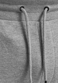 Pantalones de chándal grises con una cinturilla acanalada, cordones ajustables y una textura de tela suave con detalles de costura lateral.