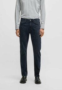 Mörkblå denimjeans med rak bendesign, femficksstil och subtila sömnadsdetaljer. Matchas med en randig skjorta med knäppning.