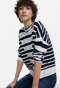 Gebreide pullover met marineblauwe en witte horizontale strepen, ronde halslijn en een ontspannen pasvorm. Gestructureerde stof met omgeslagen mouwen.