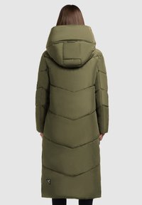 Dlhý olivovo zelený prešívaný kabát s chevronovým vzorom, oversized kapucňou a bočnými vreckami. Hladká, matná štruktúra.