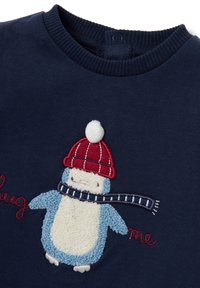 Suéter azul marino con un pingüino texturizado en azul y blanco que lleva un gorro rojo con pom-pom y una bufanda a rayas azul marino bordada en el frente.