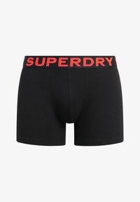 Calzoncillos boxer negros con una cinturilla elástica roja que presenta el logo "SUPERDRY". Fabricados con una tela suave, tienen un ajuste ceñido y un diseño clásico.