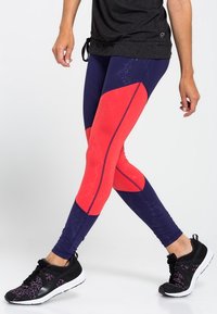 Färgglada träningsleggings med en blandning av djupt lila och starkt röd med geometriska mönster och kontrasterande sömmar; elastisk tyg.