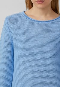 Jasnoniebieski sweter dzianinowy z teksturowanym wzorem, okrągłym dekoltem i długimi rękawami, charakteryzujący się luźnym krojem i przewiewnym materiałem.