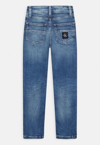 Jeans de mezclilla azul con corte recto, que cuentan con dos bolsillos traseros y una pequeña etiqueta de la marca en el bolsillo derecho. Textura suave, acabado desgastado.