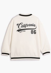 Hvid sweatshirt med "California" og "New York" trykt i sort over ryggen, med ribbet krave og manchetter i sort og hvid stribe.