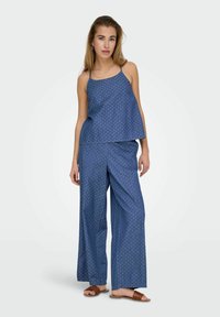 Niebieski, w kropki, lekki dwuczęściowy zestaw składający się z bezrękawnikowego topu i spodni w szerokie nogawki. Gładka tekstura i luźny krój.