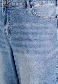 Ljusblå denimjeans med en urblekt textur, med femfickorsdesign, knäppning och subtila sömnadsdetaljer vid sömmarna.