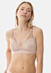 Bralette rose clair avec un design en dentelle, des panneaux en maille transparente, des bonnets triangulaires et des fines bretelles ajustables. Texture douce et matériel minimal.