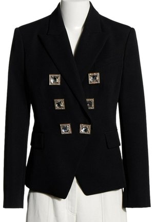 Blazer noir tailleur croisé avec six grands boutons carrés ornés de bijoux et poches à rabats, présenté sur un mannequin portant un pantalon blanc.