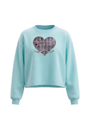 Lyseblå cropped sweatshirt med lange ærmer og et ternet hjertepatch med teksten "Be Your Own Tour Sparkle On Girl" på brystet.