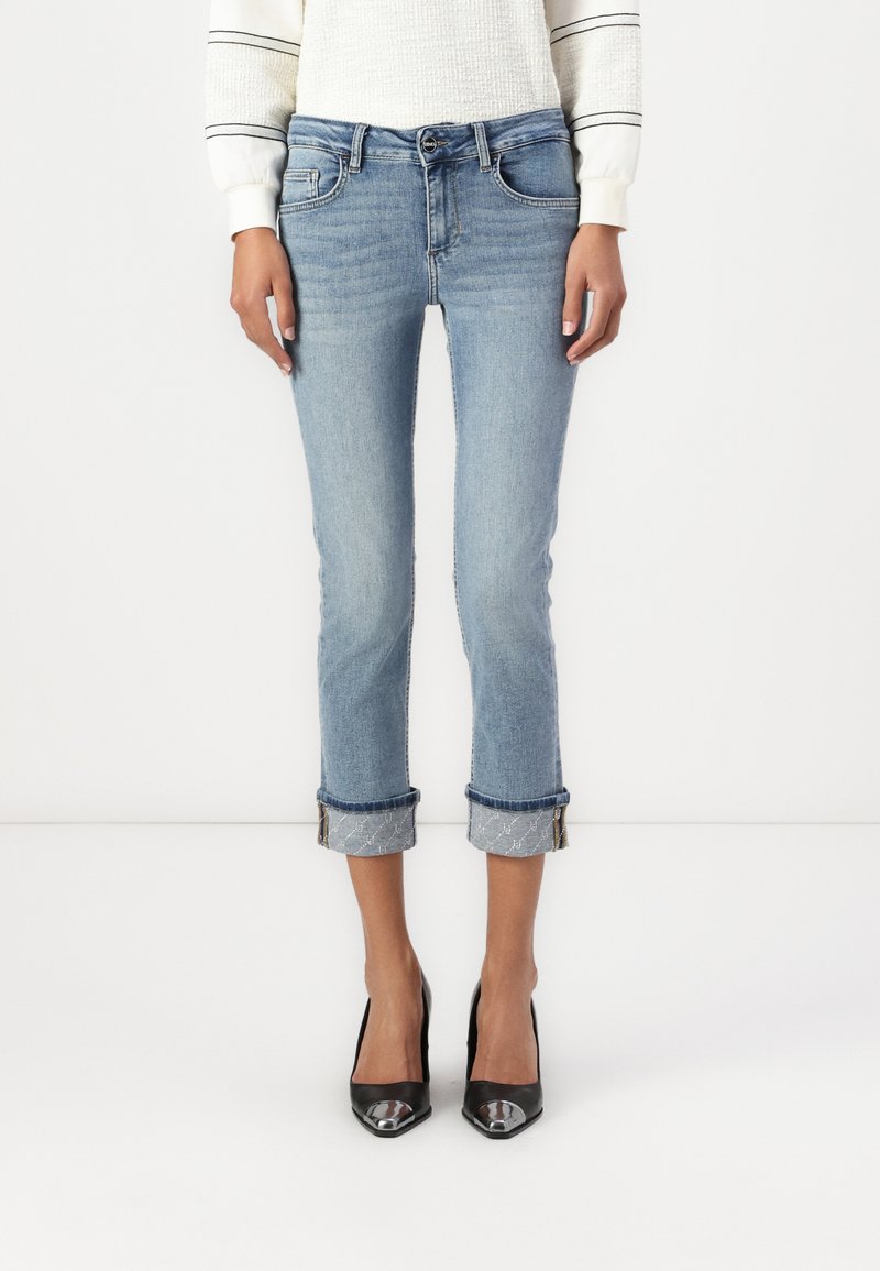 Jeans de mezclilla clara con un ajuste slim, longitud cropped y puños enrollados. Con cinco bolsillos y un cierre de botón único.