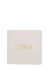 Kwadratowy, jasnoróżowy produkt z wytłoczonym złotym napisem "amor". Gładka tekstura, minimalistyczny design z subtelną ramką. Kontrastujący akcent kolorystyczny.