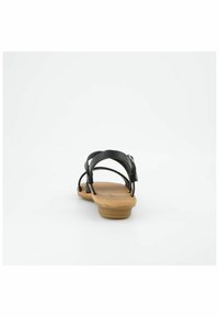 Černé kožené sandály s několika popruhy, s béžovou gumovou podrážkou a detaily s přezkou na zadní straně. Plochý design vhodný pro volnočasové nošení.