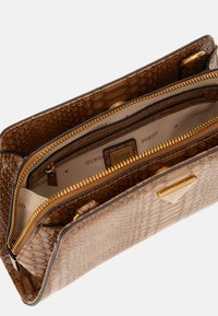 Clutch in finta pelle di serpente con texture marrone e hardware dorato, dotata di più scomparti, cerniere e del logo 'GUESS' all'interno.