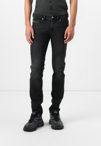 Jeanși din denim negru, cu un croi slim, având o textură netedă, cinci buzunare și un logo al mărcii contrastant pe buzunarul din spate stânga.