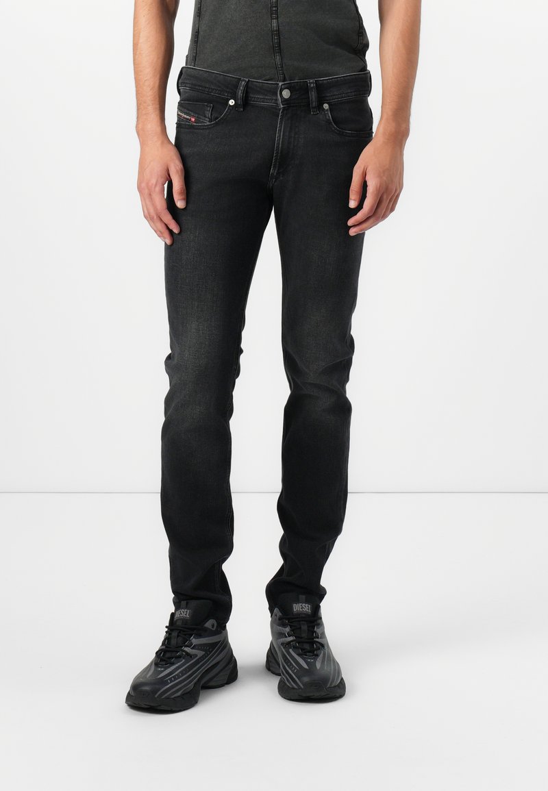 Jeanși din denim negru, cu un croi slim, având o textură netedă, cinci buzunare și un logo al mărcii contrastant pe buzunarul din spate stânga.