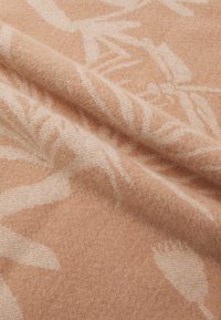 Peach-colored fabric with a soft, fuzzy texture, featuring a botanical pattern in lighter tones. The design includes abstract leaf shapes.