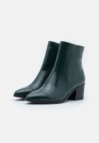 Zelené kožené ankle boty z faux kůže s texturovaným krokodýlím vzorem, špičatou špičkou a skromným blokovým podpatkem.