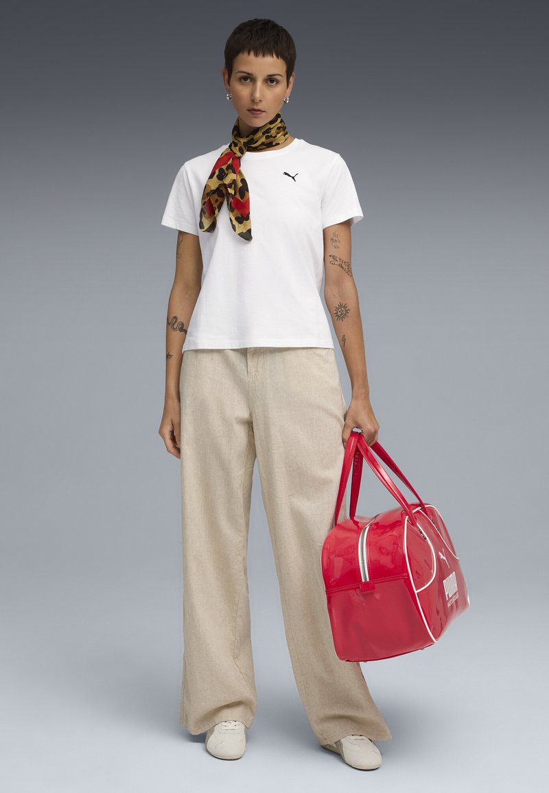 Witte t-shirt met korte mouwen, beige wijde broek, dierenprint sjaal en glanzende rode sporttas met witte accenten. Casual schoeisel maakt de look compleet.