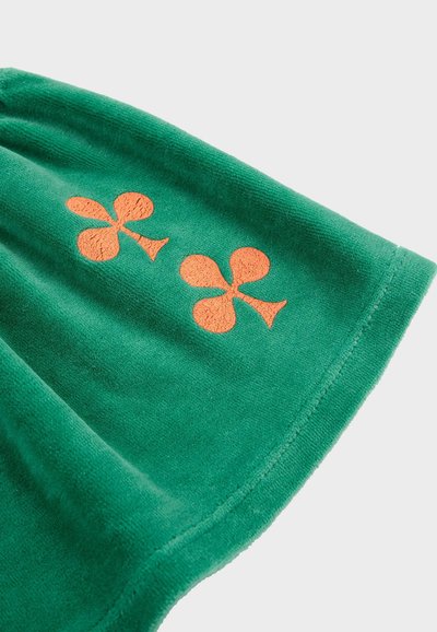 Serviette verte avec texture douce ornée de deux motifs de trèfle brodés en orange. Bord arrondi et couture régulière sur le contour.