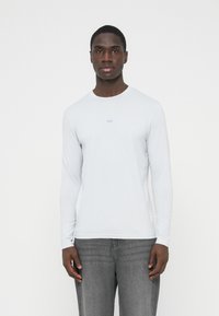 Helehall pikad varrukadega särk ümarselja ja õrna rinnakirjaga, tehtud siledast ja pehmest materjalist. Sellega kaasnevad hallid teksad.