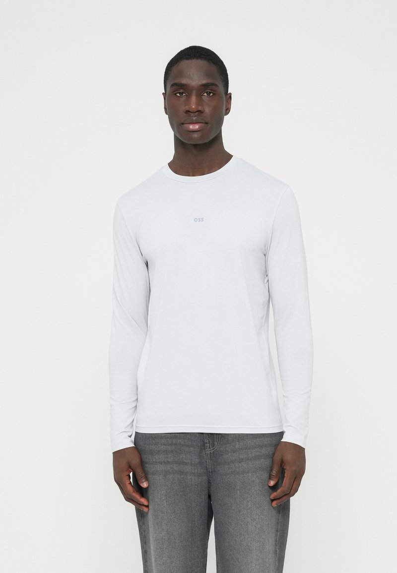 Helehall pikad varrukadega särk ümarselja ja õrna rinnakirjaga, tehtud siledast ja pehmest materjalist. Sellega kaasnevad hallid teksad.