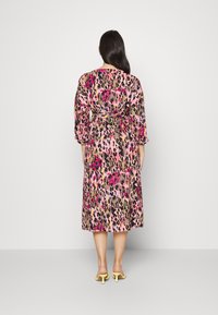 Vestido midi com padrão de leopardo nas tonalidades de rosa, preto e dourado, apresentando mangas longas e uma cintura cinturada para dar forma.