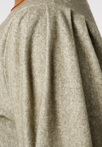 Lichtgroene trui van een zacht, textuurstof. Heeft een pofmouwontwerp en horizontale naden, wat zorgt voor een ontspannen pasvorm.