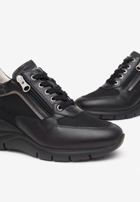 Des baskets noires avec un mélange de cuir lisse et de maille respirante. Dotées d'une fermeture éclair latérale et de lacets, avec une semelle compensée rembourrée.