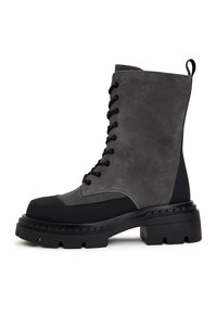 Grijze veterschoen tot de enkel, gemaakt van suede en synthetisch leer, met een chunky zwarte zool, gotische details en een ronde neus.