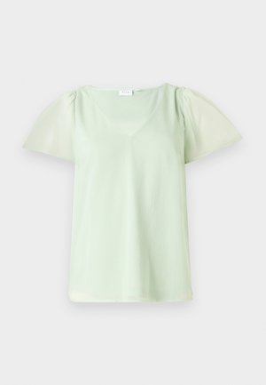 Blouse vert clair avec un col en V, manches courtes bouffantes et un tissu texturé. Fini lisse, conception légère et fluide.