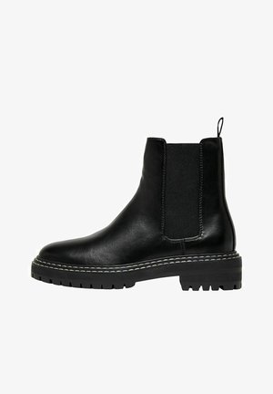 Botín de piel negra hasta el tobillo con paneles laterales elásticos, punta redonda y suela gruesa. Presenta costuras en contraste y una pestaña en la parte trasera.