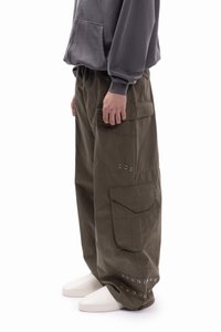 Cargo hlače maslinasto zelene boje, s velikim bočnim džepovima, ležernog kroja i srebrnim metalnim nitnama na rubu. Izrađene od čvrste tkanine.