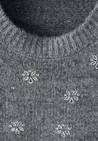 Szary, dzianinowy sweter z żeberkowym, okrągłym dekoltem, zdobiony kwiatowymi aplikacjami i cekinami. Miękka faktura, średnia grubość.