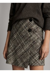 Gonna a quadri marroni realizzata in tessuto testurizzato, con design a portafoglio e due grandi bottoni neri in vita.