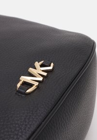 Coin de sac en cuir noir texturé avec détail de logo en métal doré fixé par des boucles en cuir noir.