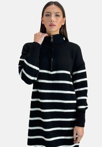 Schwarz-weißer gestreifter Strickkleid mit hohem Kragen und einem Reißverschluss vorne. Gerippte Ärmelbündchen und eine lockere Passform. Auffällige horizontale Streifen.